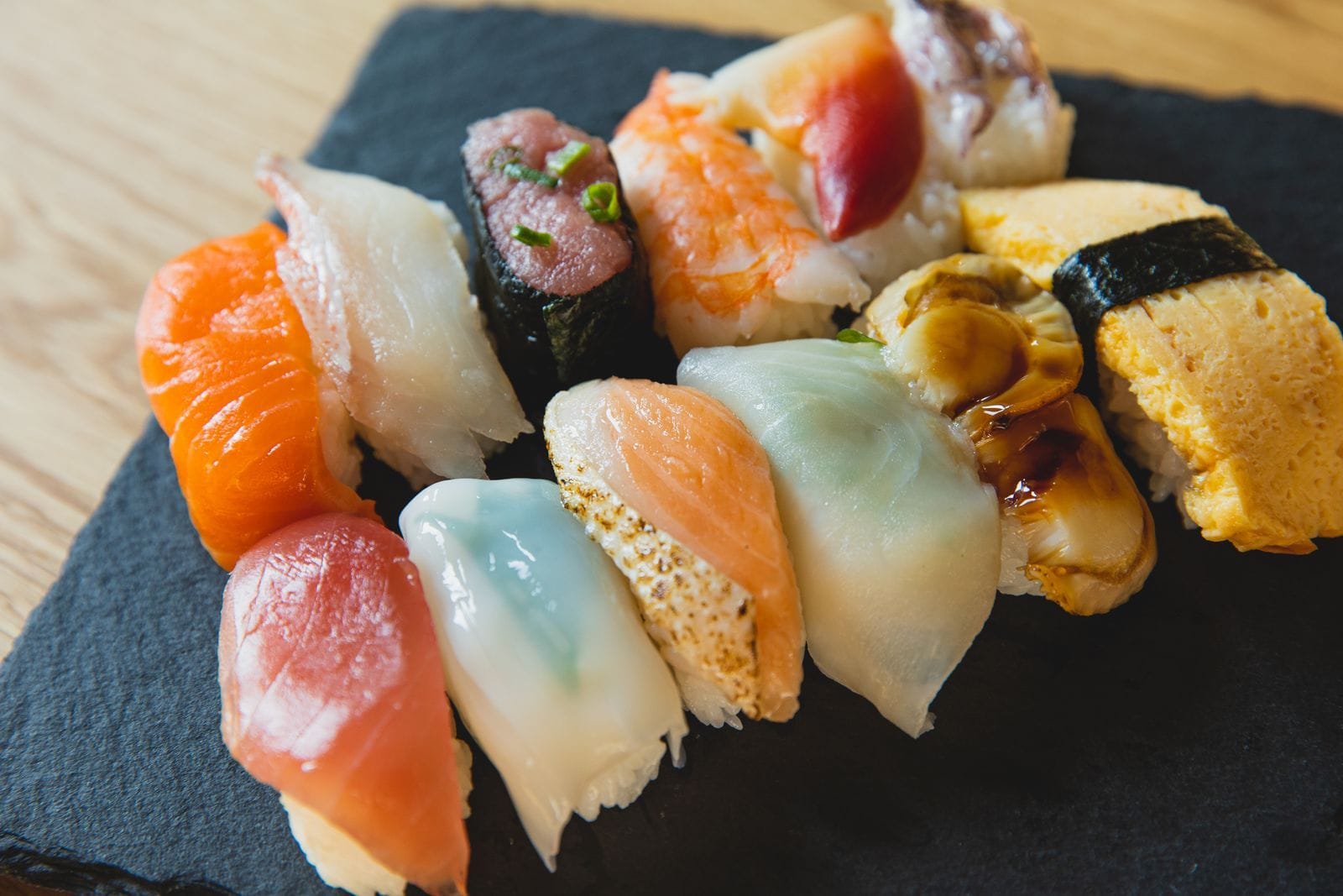Assorted nigiri sushi on a black tray